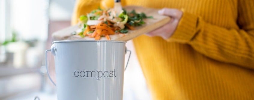 close-up-of-woman-making-compost-from-vegetable-leftovers-in-kitchen