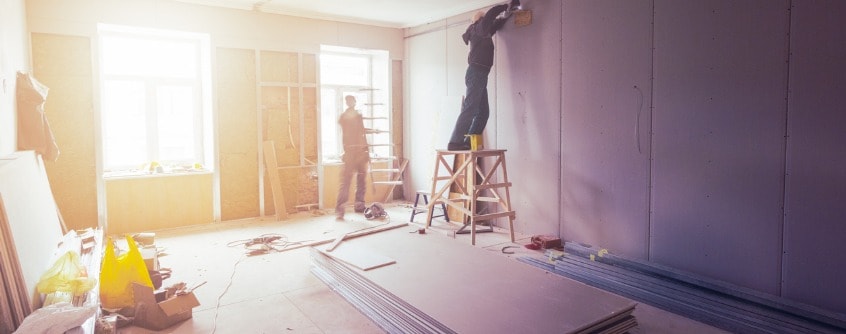 workers are installing plasterboard for gypsum walls in apartment